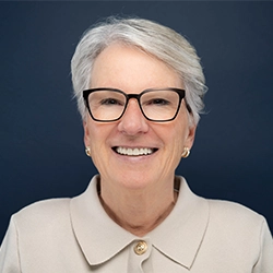 LeAnn Ridgeway smiles into the camera against a dark blue background.